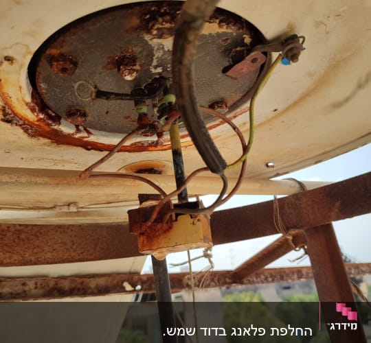 חלק תחתון של דוד שמש עם חיבורים חשמליים וחלודה